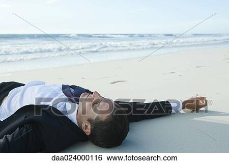 Businessman lying on sand, at beach View Large Photo Image Stock Photograph - Businessman lying on sand, at beach. Fotosearch