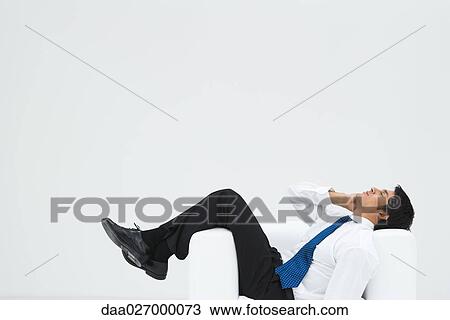 Businessman lying sideways in armchair, making phone call, full length View Large Photo Image Stock Image - Businessman lying sideways in armchair, making phone call, full length. Fotosearch