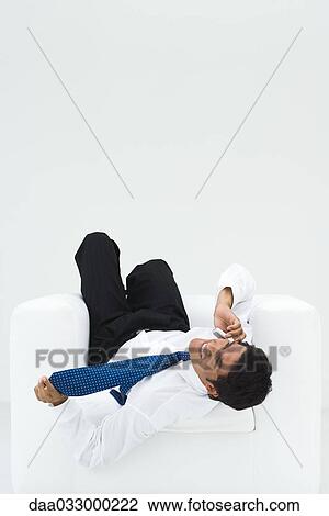 Businessman lying upside down in armchair, talking on the phone View Large Photo Image Stock Image - Businessman lying upside down in armchair, talking on the phone. Fotosearch