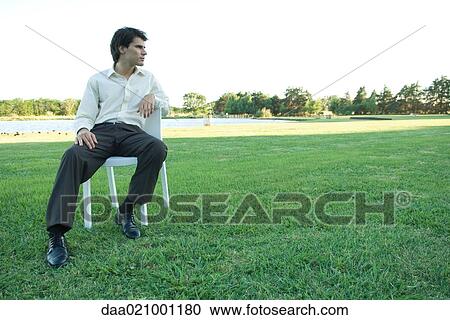 Businessman sitting in chair on lawn, looking away View Large Photo Image Stock Image - Businessman sitting in chair on lawn, looking away. Fotosearch
