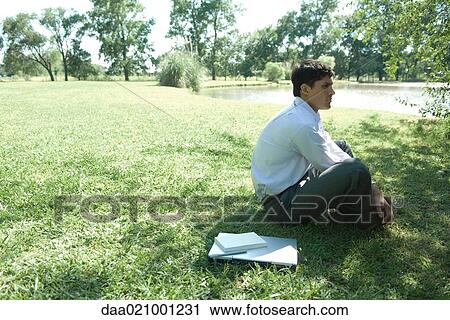 Businessman sitting on grass, laptop closed by side View Large Photo Image Stock Image - Businessman sitting on grass, laptop closed by side. Fotosearch