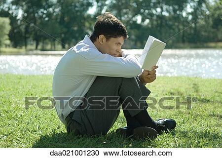 Businessman sitting on grass, reading View Large Photo Image Stock Image - Businessman sitting on grass, reading. Fotosearch