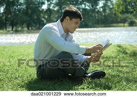 Businessman sitting on grass, reading View Large Photo Image Stock Photo - Businessman sitting on grass, reading. Fotosearch