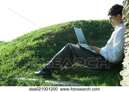 Businessman sitting on ground, using laptop View Large Photo Image Stock Image - Businessman sitting on ground, using laptop. Fotosearch