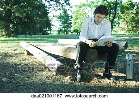 Businessman sitting on logs, reading documents View Large Photo Image Stock Photo - Businessman sitting on logs, reading documents. Fotosearch