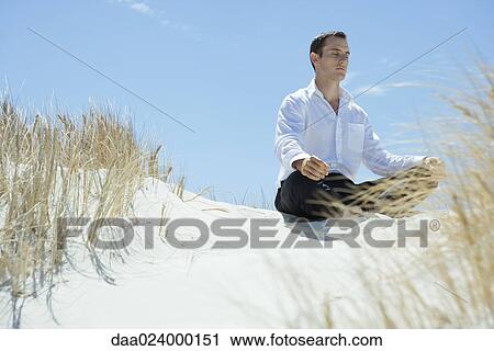 Businessman sitting on sand dune, meditating View Large Photo Image Stock Image - Businessman sitting on sand dune, meditating. Fotosearch