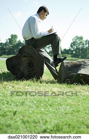 Businessman sitting on tree trunk, working View Large Photo Image Stock Image - Businessman sitting on tree trunk, working. Fotosearch
