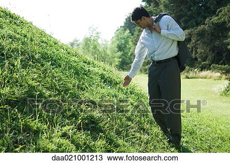 Businessman standing by grassy hill, holding out hand View Large Photo Image Stock Image - Businessman standing by grassy hill, holding out hand. Fotosearch