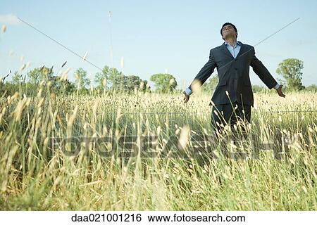 Businessman standing in field, arms out, head back and eyes closed View Large Photo Image Stock Photograph - Businessman standing in field, arms out, head back and eyes closed. Fotosearch