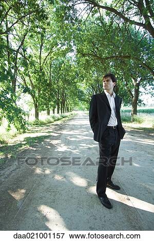 Businessman standing in rural road, full length View Large Photo Image Stock Photo - Businessman standing in rural road, full length. Fotosearch
