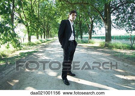 Businessman standing in rural road, full length View Large Photo Image Stock Photograph - Businessman standing in rural road, full length. Fotosearch