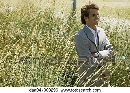 Businessman standing in tall grass with arms folded looking away View Large Photo Image Stock Photograph - Businessman standing in tall grass with arms folded looking away. Fotosearch