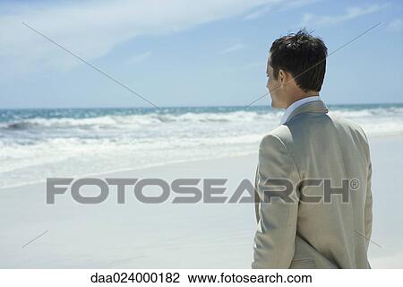 Businessman standing on beach, looking at ocean, waist up View Large Photo Image Stock Image - Businessman standing on beach, looking at ocean, waist up. Fotosearch