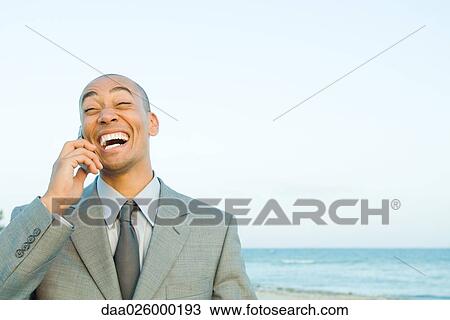 Businessman using cell phone at the beach, smiling, eyes closed View Large Photo Image Stock Image - Businessman using cell phone at the beach, smiling, eyes closed. Fotosearch