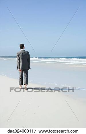 Businessman walking barefoot on beach, rear view View Large Photo Image Stock Photo - Businessman walking barefoot on beach, rear view. Fotosearch