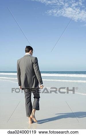 Businessman walking barefoot on beach, rear view View Large Photo Image Stock Photo - Businessman walking barefoot on beach, rear view. Fotosearch