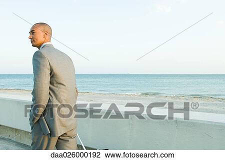 Businessman walking by the sea, looking away View Large Photo Image Stock Image - Businessman walking by the sea, looking away. Fotosearch