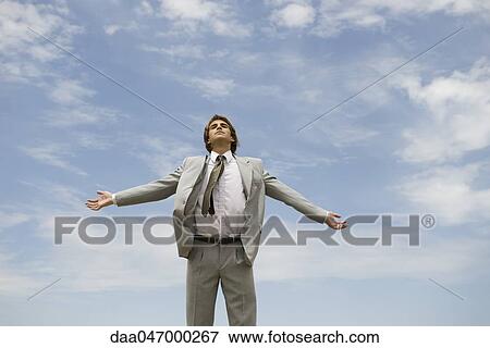 Businessman with arms outstretched against cloudy sky View Large Photo Image Stock Photo - Businessman with arms outstretched against cloudy sky. Fotosearch