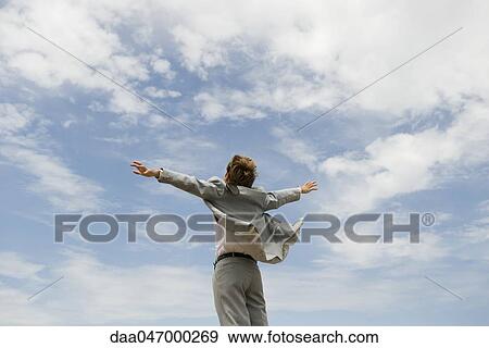 Businessman with arms outstretched against cloudy sky, rear view View Large Photo Image Stock Photo - Businessman with arms outstretched against cloudy sky, rear view. Fotosearch