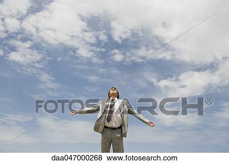 Businessman with head back, arms outstretched against cloudy sky View Large Photo Image Stock Photo - Businessman with head back, arms outstretched against cloudy sky. Fotosearch