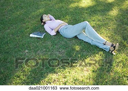 Businesswoman lying in grass, eyes closed View Large Photo Image Stock Image - Businesswoman lying in grass, eyes closed. Fotosearch