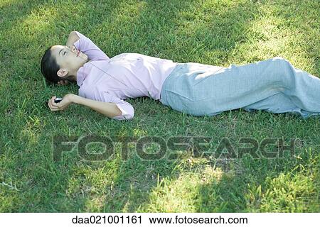 Businesswoman lying in grass, holding cell phone View Large Photo Image Stock Image - Businesswoman lying in grass, holding cell phone. Fotosearch