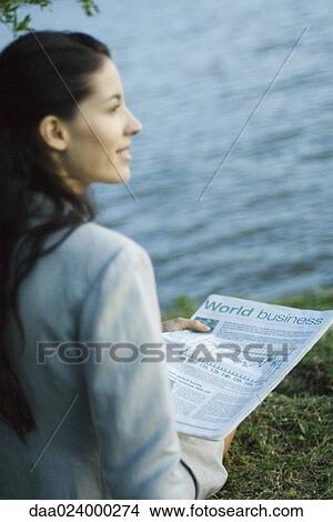 Businesswoman reading newspaper, lake in background View Large Photo Image Picture - Businesswoman reading newspaper, lake in background. Fotosearch