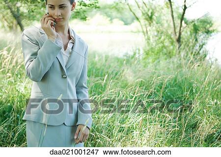 Businesswoman standing in field, using cell phone View Large Photo Image Stock Photo - Businesswoman standing in field, using cell phone. Fotosearch