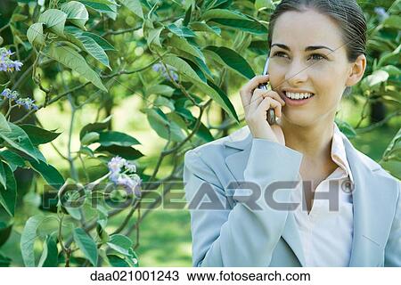 Businesswoman standing in vegetation, using cell phone View Large Photo Image Stock Image - Businesswoman standing in vegetation, using cell phone. Fotosearch