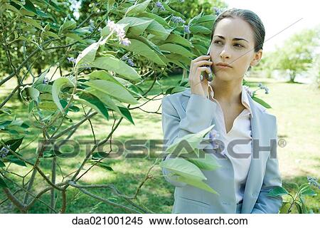 Businesswoman standing in vegetation, using cell phone View Large Photo Image Stock Photography - Businesswoman standing in vegetation, using cell phone. Fotosearch