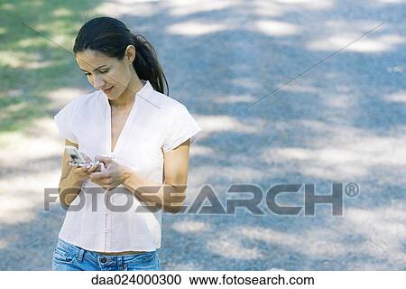 Casually dressed woman holding cell phone View Large Photo Image Stock Image - Casually dressed woman holding cell phone. Fotosearch