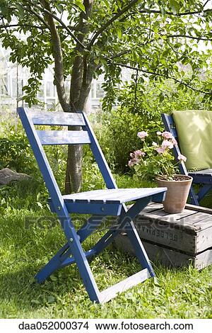 Picture - Chair next top potted geranium in backyard. Fotosearch