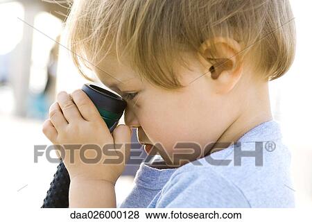Stock Photo - Child holding flashlight against face, side view, close-up. Fotosearch