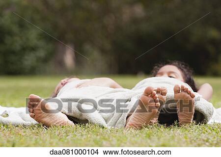 Children lying together under blanket on grass View Large Photo Image Picture - Children lying together under blanket on grass. Fotosearch