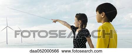 Stock Photograph - Children pointing to wind turbines in distance. Fotosearch