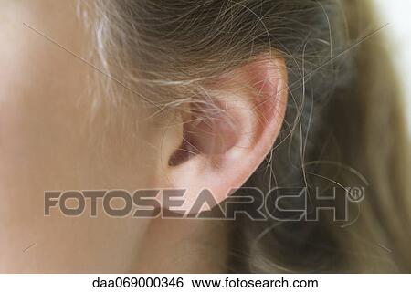 Stock Photograph - Close-up of young woman's pierced ear. Fotosearch