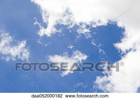 Stock Image - Commercial airplane flying through cloudscape. Fotosearch