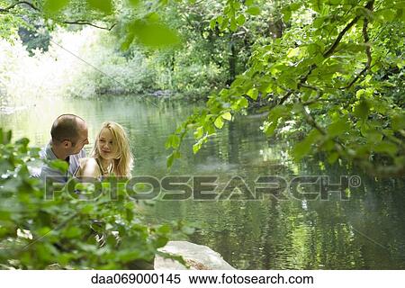Stock Photography - Couple by river, looking at each other affectionately. Fotosearch