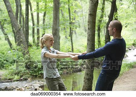Couple holding hands around tree in woods View Large Photo Image Picture - Couple holding hands around tree in woods. Fotosearch