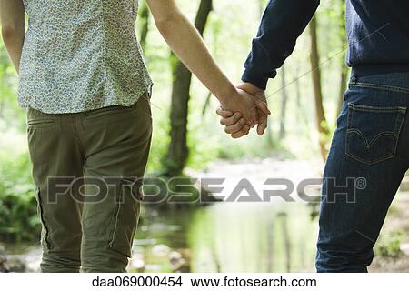 Couple holding hands in nature, mid section View Large Photo Image Picture - Couple holding hands in nature, mid section. Fotosearch