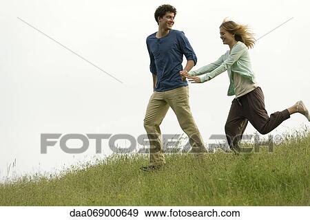 Couple holding hands running on meadow View Large Photo Image Stock Photo - Couple holding hands running on meadow. Fotosearch