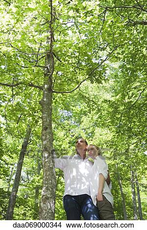Picture - Couple in woods, low angle view. Fotosearch