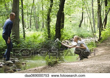 Couple in woods, woman splashing water at man View Large Photo Image Stock Image - Couple in woods, woman splashing water at man. Fotosearch