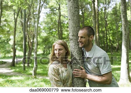 Couple leaning against tree trunk View Large Photo Image Stock Photo - Couple leaning against tree trunk. Fotosearch
