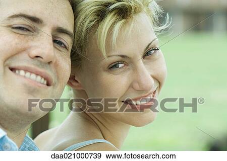 Couple leaning heads together, smiling at camera, close-up View Large Photo Image Stock Photo - Couple leaning heads together, smiling at camera, close-up. Fotosearch