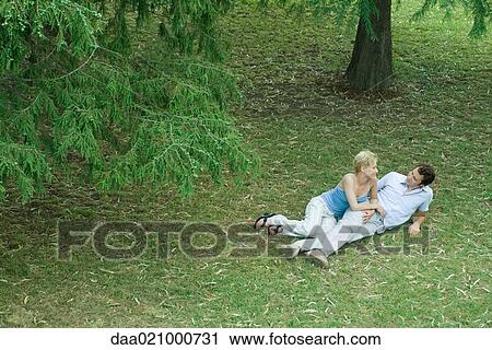 Couple lying in grass, smiling at each other, full length, high angle view View Large Photo Image Stock Image - Couple lying in grass, smiling at each other, full length, high angle view. Fotosearch