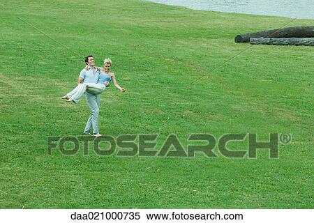 Couple on lawn, man holding woman in arms View Large Photo Image Stock Photography - Couple on lawn, man holding woman in arms. Fotosearch