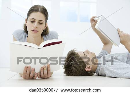 Stock Photo - Couple reading books, man lying on back, woman lying on stomach. Fotosearch