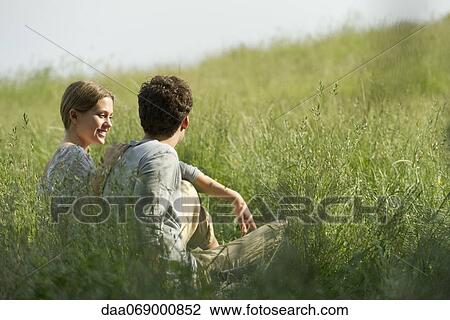 Stock Image - Couple relaxing in grass. Fotosearch
