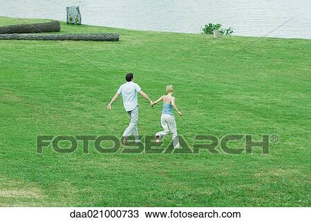 Couple running across grass, hand in hand, full length, high angle view View Large Photo Image Stock Image - Couple running across grass, hand in hand, full length, high angle view. Fotosearch